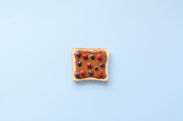 Toast with peanut butter and berries on a blue background.