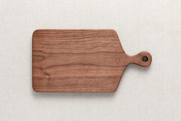 Walnut handmade wood cutting board on the linen.