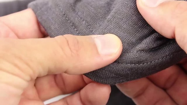 human hand testing gray synthetic thermal underwear, close-up(macro)