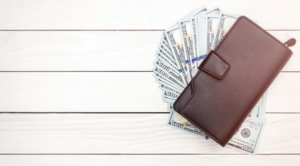 Men's black wallet with dollar bills on wooden table. Top view. Space for text. Toned image.