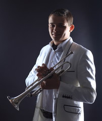 young man in a white suit with a trumpet.isolated on black background