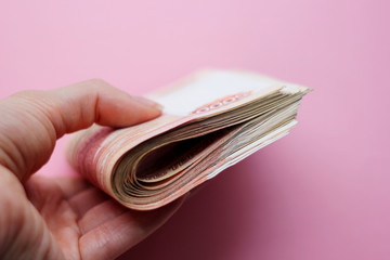 A stack of bills in denominations of 5000 rubles in hand. Russian money.Scissors cut a stack of...