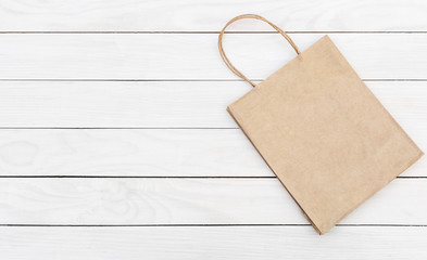 Paper shopping bag on white wooden background. Space for text.
