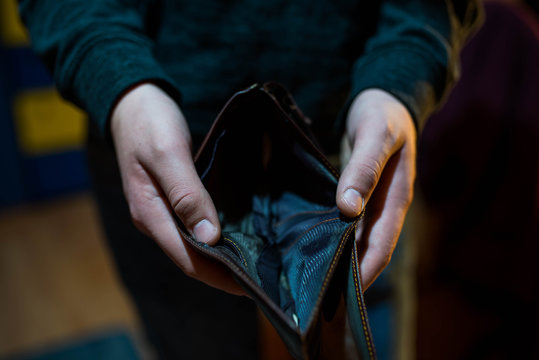 Young man holding the empty wallet , focus on the hand, conceptual image of underpaid work.