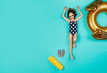 Happy girl in swimsuit lying on blue background