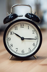 closeup of vintage alarm clock on wooden table on blurred background