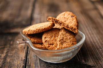 Integral cookies with cereal, dried fruit and chocolate on old wooden table