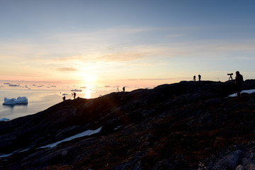 People silhouette on the mountain peak at Greenland