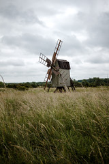 Naklejka premium Alte Windmühle aus Holz aus dem Feld. Düstere Stimmung. Dunkle Wolken