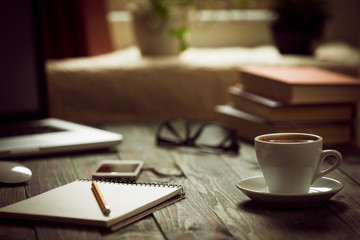 A cup of coffee in the workplace on a wooden table.