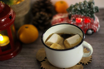 Coffee with marshmallow in a white cup on a blurred wooden background. In frame view a red lantern, mandarins. Holiday concept