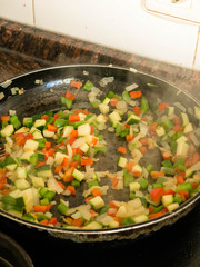 Making, cooking onion, red and green pepper and courgette in a frying pan
