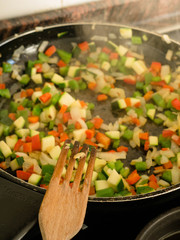 Making, cooking onion, red and green pepper and courgette in a frying pan