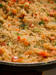 Mixing quinua with onion, red and green pepper and courgette in a frying pan. Cooking quinua with vegetables, recipe of quinua and vegetables