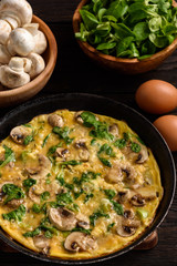 Omelette with mushrooms and cheese, on dark wooden background.
