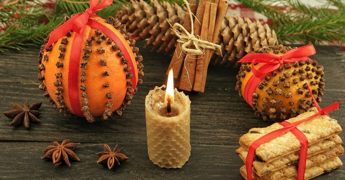 Decorative Christmas composition with pomander and a burning candle on the background of a wooden board