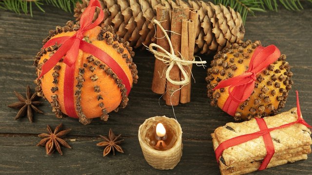 Decorative Christmas composition with pomander and a burning candle on the background of a wooden board