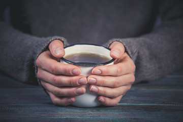 Woman holds a cup of hot tea. Cozy morning at home.