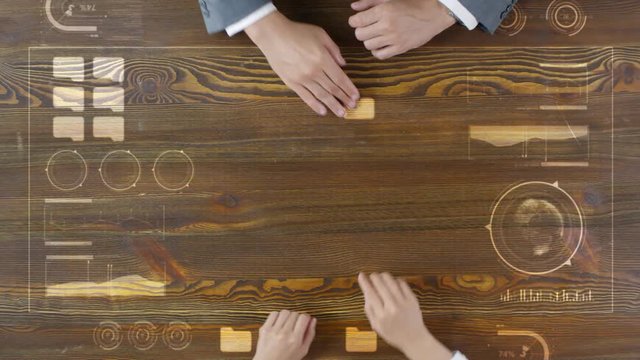 Top view of hands of man and woman using augmented reality interface on wooden surface. They swiping and tapping for opening folder with animated business data