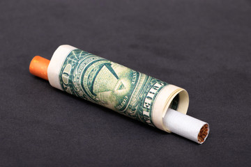 A single cigarette in a dollar bill