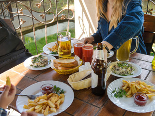 The family is having lunch at the cafe. On the table, French fries, salad, bread, tomato juice, beer, tableware.
