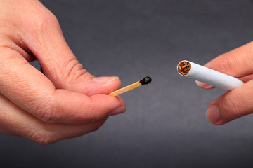 Woman hand burning a cigarette with a match