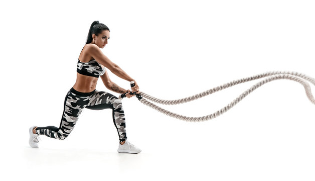 Athletic Woman Workout With Heavy Ropes. Photo Of Sporty Woman In Fashionable Sportswear Isolated On White Background. Strength And Motivation. Side View.