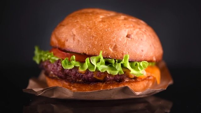Cheeseburger rotated on black background. Fresh Hamburger on fresh buns with succulent beef and fresh salad ingredients isolated on black. Slow motion 4K UHD video