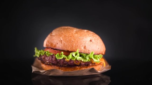 Cheeseburger rotated on black background. Fresh Hamburger on fresh buns with succulent beef and fresh salad ingredients isolated on black. 4K UHD video footage. 3840X2160