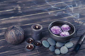 Singing bowl with candles with pebbles on dark wooden background