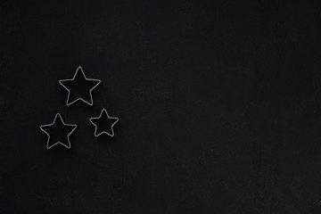 Metal stars on black festive background. Baking molds. Cookie cutters. Flat lay, top view
