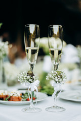 two glasses of champagne on a table with lilies of the valley