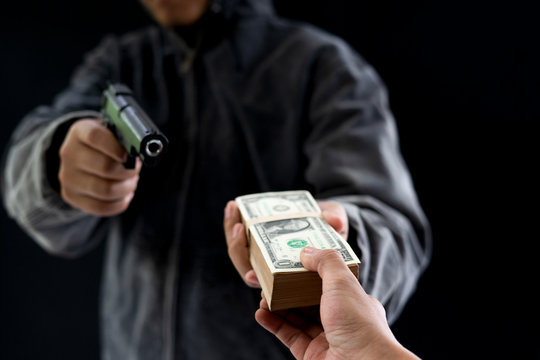Robbery with gun's. Gun and money in a hands. Bank robbery, Man carrying a gun to rob the bank note. To threaten with the man. A murderer attacking holding gun kidnapping business young person.