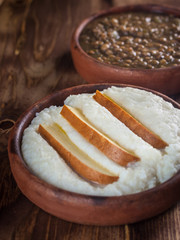 Mengrelian corn mamalica (ghomi) with cheese and lentls in ceramic dish (ketsi). Georgian traditional food