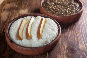 Mengrelian corn mamalica (ghomi) with cheese and lentls in ceramic dish (ketsi). Georgian traditional food