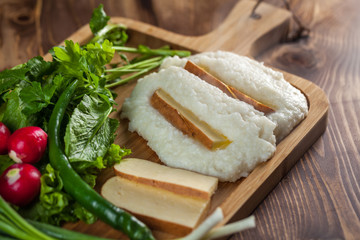 Mengrelian corn mamalica (ghomi) with cheese and various herb on wooden table. Georgian traditional food