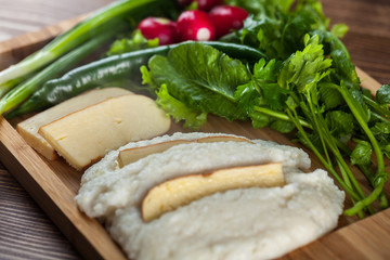 Mengrelian corn mamalica (ghomi) with cheese and various herb on wooden table. Georgian traditional food
