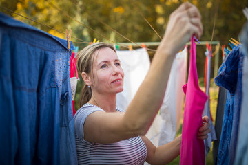 Young woman putting laundry on a rope in her garden,  taking great care of her family on a daily basis