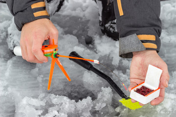 A man holds a small orange fishing pole for fishing.