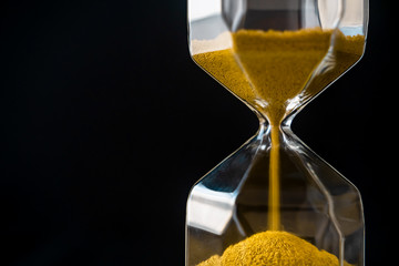 The sand flow in the hourglass with black background