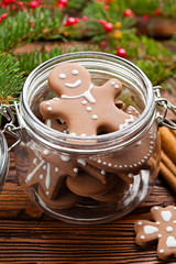 Gingerbread Christmas cookies in a jar, cinnamon, hazelnuts and branch of spruce tree on wooden table
