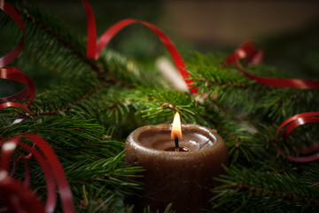 Wooden background with branches of a Christmas tree and a red candle.