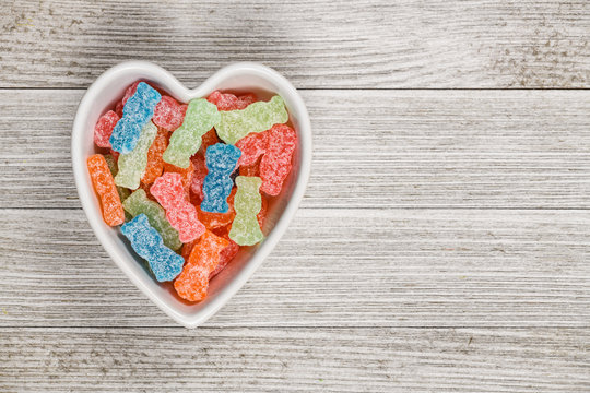 Variety Of Different Color Sweet And Sour Candy Or Sugar Junk Food In A Heart Shaped Bowl.