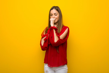 Young girl with red dress over yellow wall is suffering with cough and feeling bad