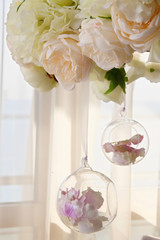 In a transparent glass flask there are flowers buds or petals of pink color.