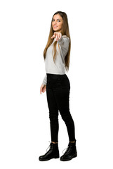 Full-length shot of young girl points finger at you with a confident expression on isolated white background