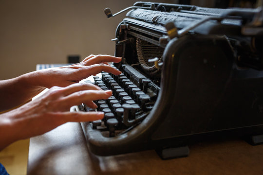 woman hands type on an old vintage dust-covered typewriter