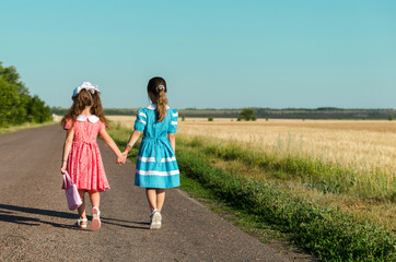 Две девочки иду по дороге взявшись за руки. 