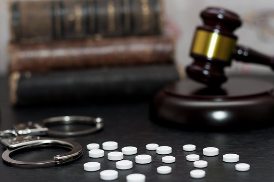Judge's gavel with handcuffs, drugs on wooden table