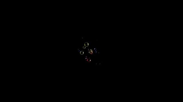 Colorful tiny soap bubbles appearing from a fixed source on a black background, disappearing with a pop.
